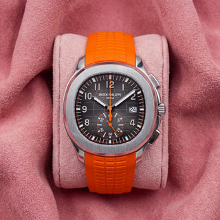 Patek Philippe Aquanaut 5968A with black patterned dial, orange accents and orange textured strap on a pink cushion