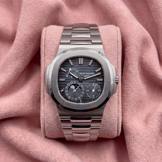 Patek Philippe Nautilus 5712/1A-001 with blue-grey striped moon-phase dial and integrated silver-toned bracelet on a pink cushion