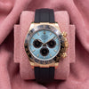 Front view of turquoise-blue dial Daytona with black chronograph registers, dark bezel and black strap on pink cushion