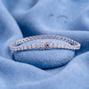 Platinum round brilliant-cut diamond tennis bracelet on a soft blue background