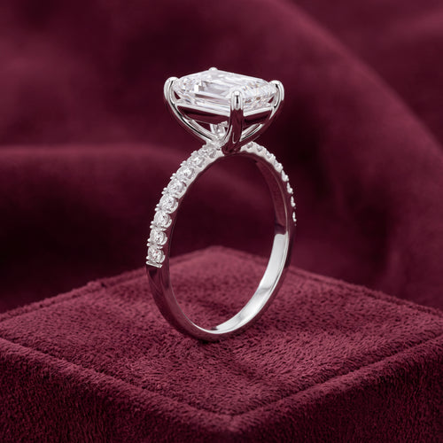 Side view of platinum emerald-cut engagement ring showing four-claw setting and diamond shoulders