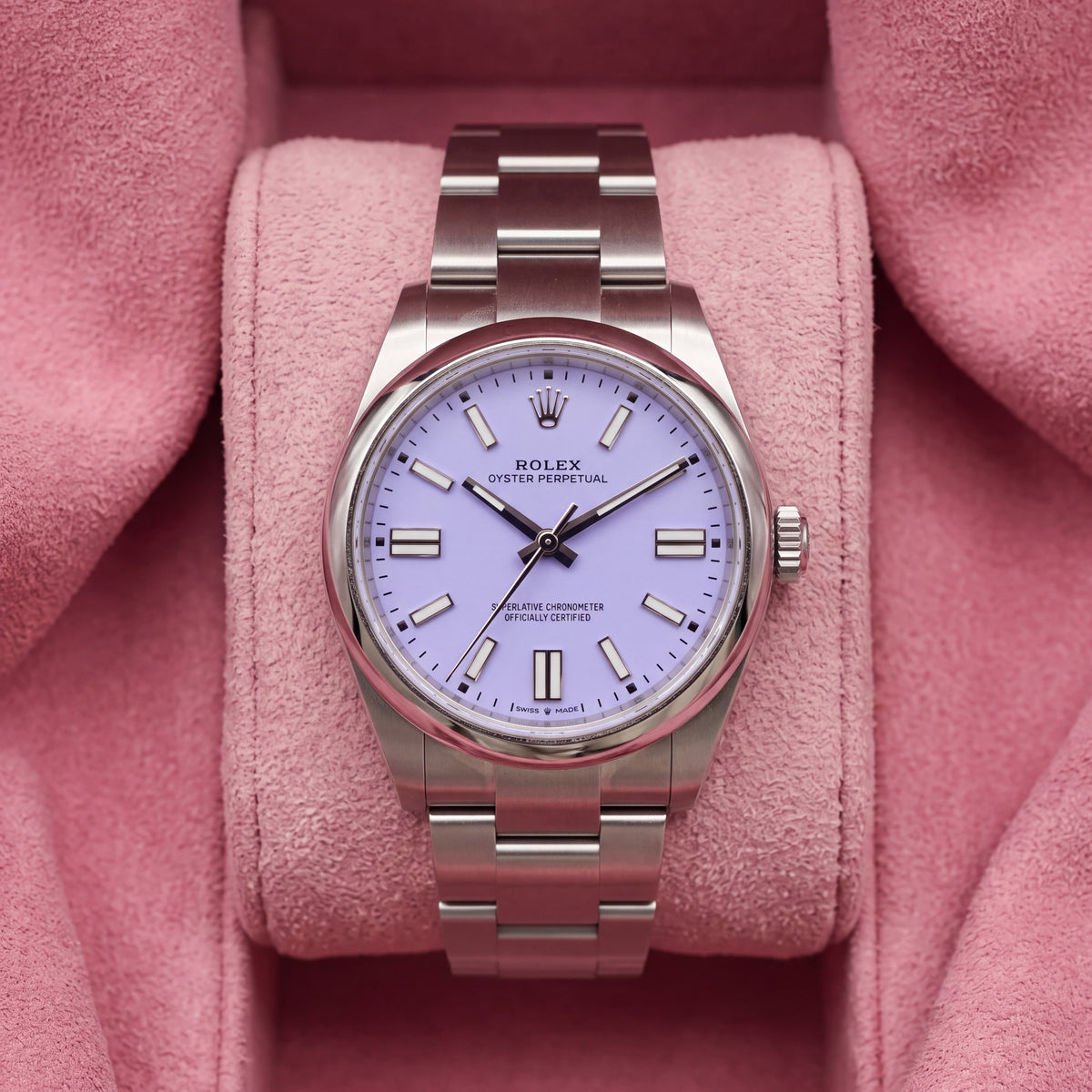 Front view of lavender-dial Oyster Perpetual watch with smooth steel bezel and Oyster bracelet on pink cushion