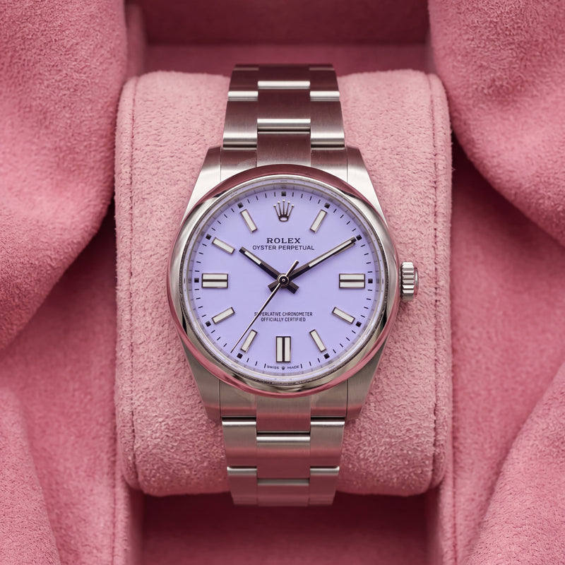 Front view of lavender-dial Oyster Perpetual watch with smooth steel bezel and Oyster bracelet on pink cushion
