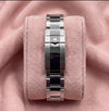 Steel watch bracelet and crown-emblem clasp shown from the rear on pink cushion