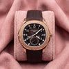 Patek Philippe Aquanaut Travel Time 5164R with rose-gold case, dark brown patterned dial and textured strap on a pink cushion