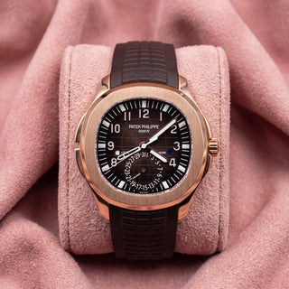Patek Philippe Aquanaut Travel Time 5164R with rose-gold case, dark brown patterned dial and textured strap on a pink cushion