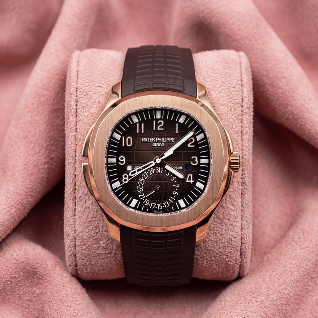 Patek Philippe Aquanaut Travel Time 5164R with rose-gold case, dark brown patterned dial and textured strap on a pink cushion