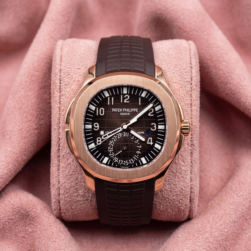 Patek Philippe Aquanaut Travel Time 5164R with rose-gold case, dark brown patterned dial and textured strap on a pink cushion