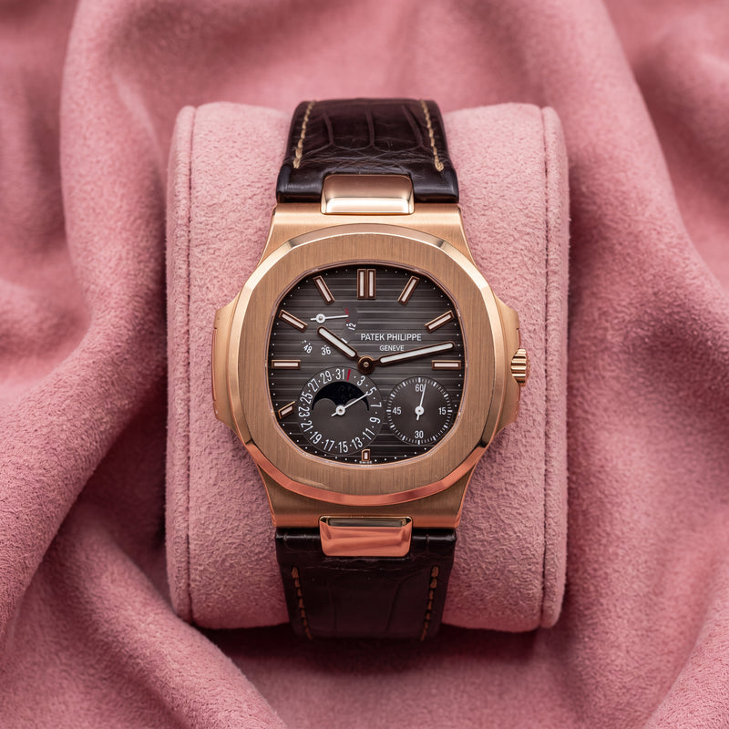 Patek Philippe Nautilus 5712R-001 with rose-toned case, dark striped moon-phase dial and brown leather strap on a pink cushion