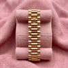Gold-tone Rolex President bracelet with crown detail on a pink cushion
