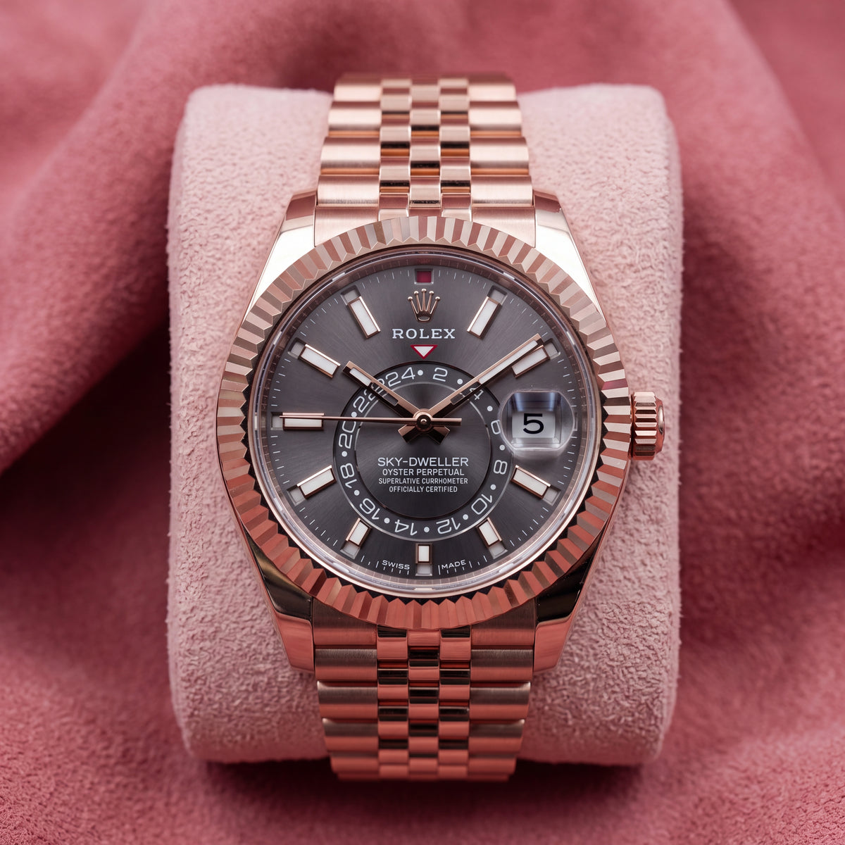 Front view of rose-tone Sky-Dweller with rhodium dial, fluted bezel and Jubilee bracelet on pink cushion