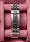 A Rolex Oyster Perpetual Datejust watch with a blue dial and stainless steel Oyster bracelet, displayed inside a pink velvet watch box alongside a matching bracelet clasp.