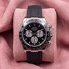 Front view of black-dial Daytona chronograph with dark tachymeter bezel and black strap on pink cushion
