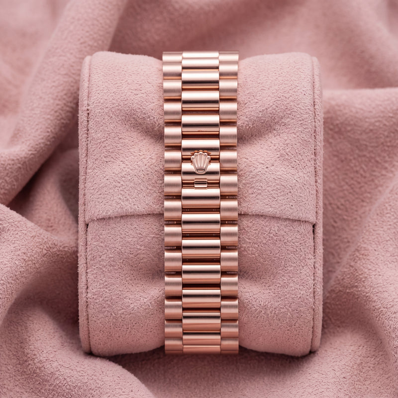 Rear view of rose-tone three-link watch bracelet with crown-emblem clasp on pink cushion