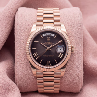 Front view of rose-tone Day-Date watch with dark ombré dial and fluted bezel on pink cushion
