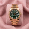 Rolex Sky-Dweller with green dial, gold-tone fluted bezel and Oyster bracelet on a pink cushion