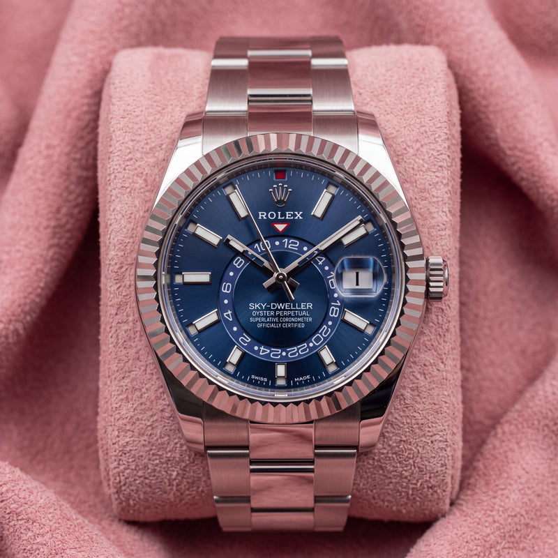 Rolex Sky-Dweller with blue dial, fluted bezel and Oyster bracelet on a pink cushion