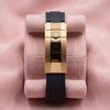Black watch strap with yellow-gold-tone crown-emblem clasp on pink cushion